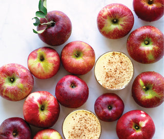 two glasses of apple chai spice surrounded by red apples
