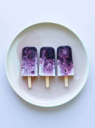 3 Blackberry Swirl Popsicles on a white plate