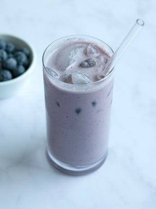 a small bowl of blueberries and a glass blueberry pie milk