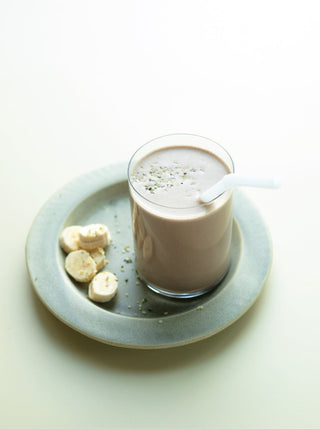 a glass of chocolate peanut butter protein shake on a green plate