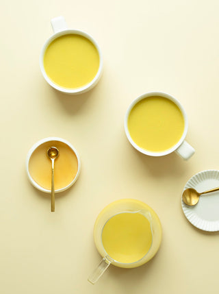 two cups and pitcher of beautiful golden spring milk