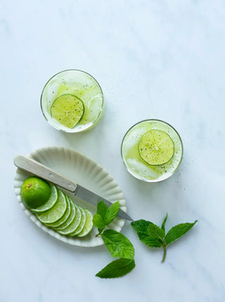 two glasses of green apple mint fizz with ingredients and a knife