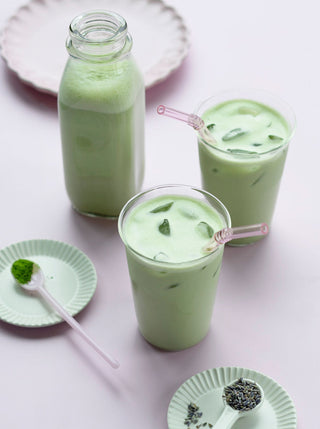 a glass bottle and two glasses of lavendar honey matcha latte