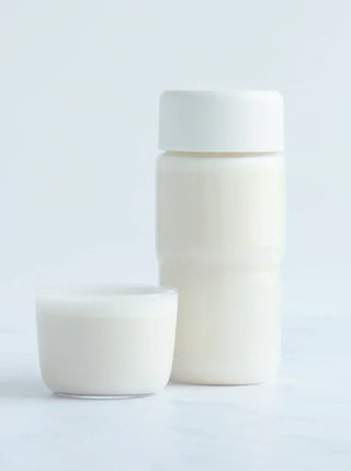 a glass and bottle both filled with almond oat milk