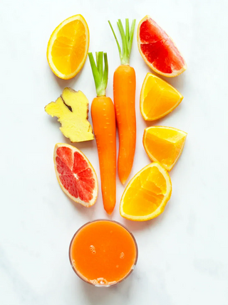 a glass of orange juice with carrots orange grapefruit and ginger