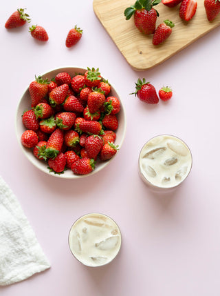 two glasses of strawberries & cardamom cream over ice with a bowl of strawberries