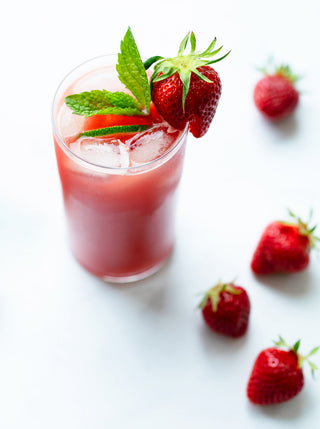 A glass of Berry Mint Burst juice with strawberries and mint on top