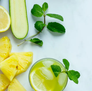 a glass of hydrating green juice garnished with lemon and mint