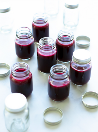 A group of small galss bottltes filled with Beet-Cranberry Booster shots