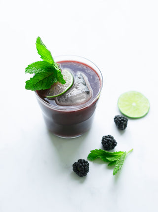 Glass of Blackberry-Lime Juice with a Kick topped with mint and slice of lime