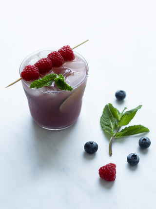 a glass of Blueberry Mojito with raspberry garnish