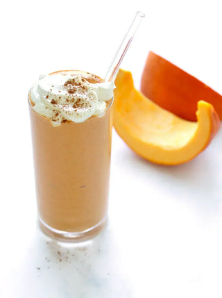 a glass of creamy pumpkin smoothie topped with whipped cream