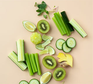 a loose pile of green fruit and vegetables on a pale orange surface