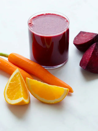 a glass of deep red juice with ingredients beets carrots and orange