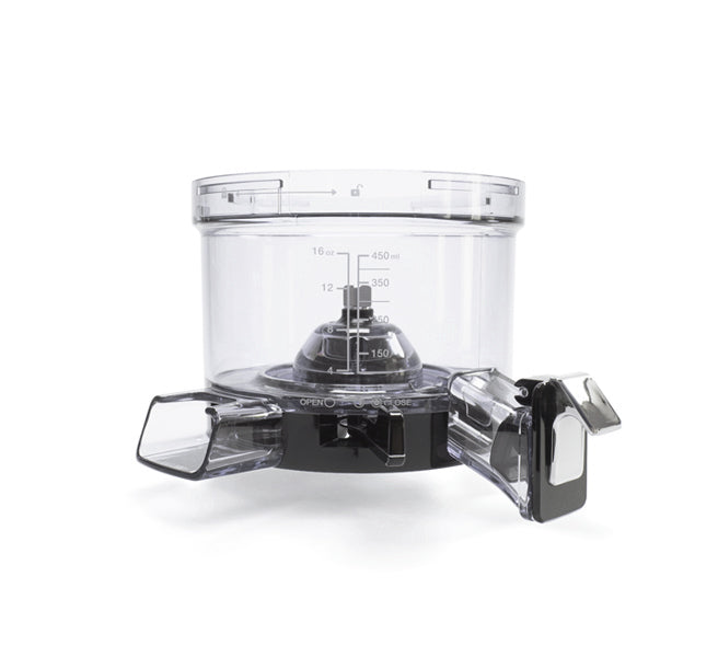 A clear plastic food processor bowl with measurement markings sits atop a black base with controls, featuring two rectangular chutes on either side for adding ingredients—similar in versatility to the Chamber Set, which utilizes a specialized chamber for efficient ingredient processing.