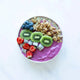 A smoothie bowl with a vibrant purple smoothie base, effortlessly blended using the Nama C2 high-performance blender, topped with sliced kiwi, blueberries, strawberries, dragon fruit cubes, and granola, beautifully arranged on a white marble surface.