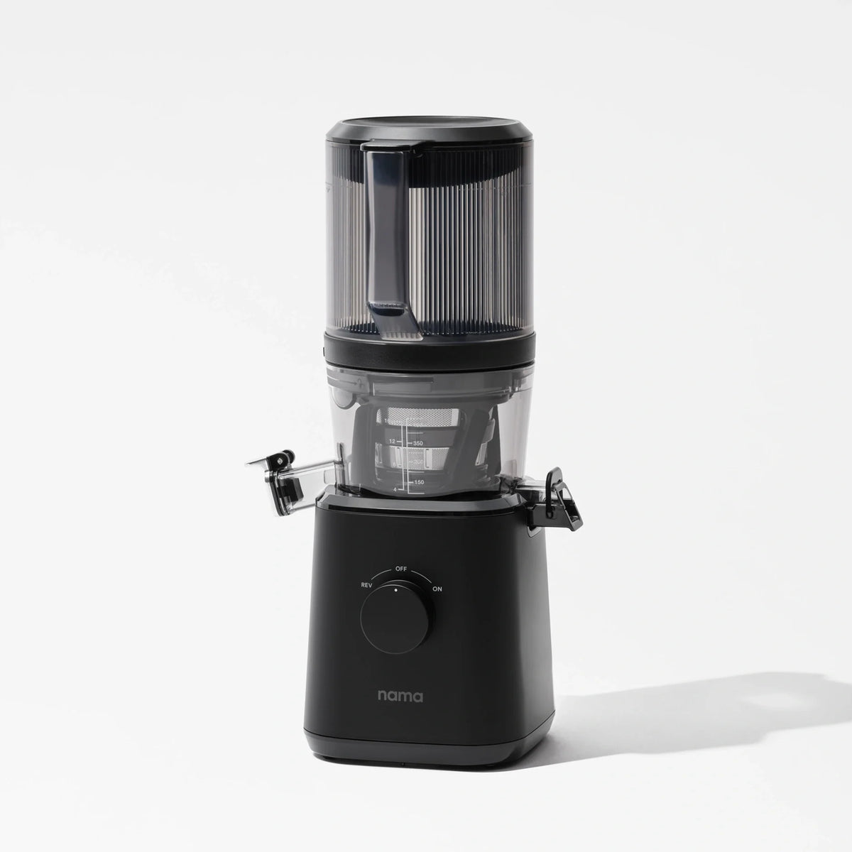 A sleek black Nama J2 juicer featuring a transparent top container and a front-facing control dial stands against a plain white background. The Nama J2 cold press juicer is engineered to provide fresh, nutrient-rich juice and boasts an easy-to-clean design for maximum convenience.