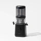 A sleek black Nama J2 juicer featuring a transparent top container and a front-facing control dial stands against a plain white background. The Nama J2 cold press juicer is engineered to provide fresh, nutrient-rich juice and boasts an easy-to-clean design for maximum convenience.