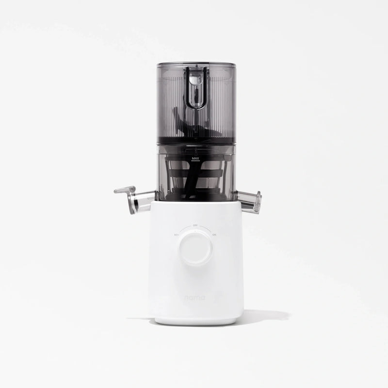 The Nama J3 is a modern cold press juicer featuring a white base, a central dial, and a transparent dark gray container on top, displayed against a plain white background.