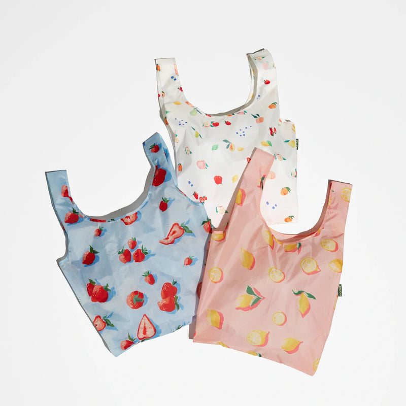 Set of three Nama + Baggu Standard Tote Bags, perfect as grocery bag options, each featuring vibrant fruit patterns: a blue tote with strawberries, a white tote with assorted fruits, and a pink tote with lemons—all arranged on a white background. These reusable bags are ideal for carrying fresh produce in style.