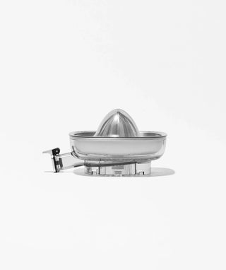 A metal citrus juicer with a ridged cone sits on a flat surface against a plain white background.