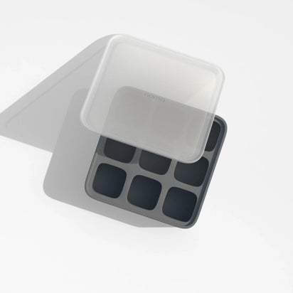 The Ice Cube Tray is made of black silicone and features eight compartments, shown with a translucent lid partially covering it and casting a shadow on a white surface.