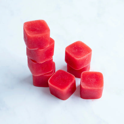A stack of six red, square-shaped Ice Cube Tray molds stands next to three more molds on a white, marble-like surface.