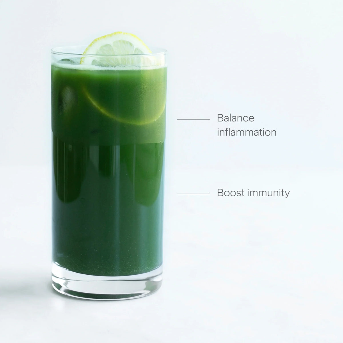 A tall glass of Gut Health green juice with ice and lemon slices, placed on a white surface. Text points to the drink, reading Balance inflammation and Boost immunity.