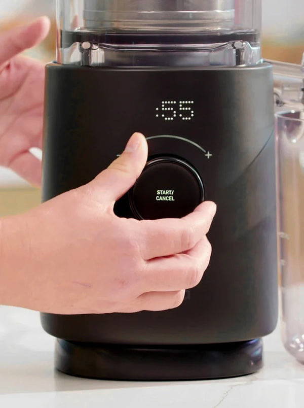 A hand turns the dial on a black kitchen appliance with an LED timer display showing 55 seconds. The dial is labeled Start/Cancel..