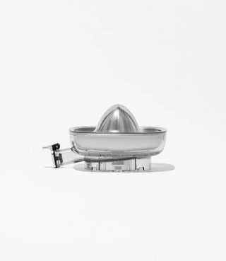 A metal citrus juicer with a conical reamer and attached handle sits on a clear base against a plain white background.