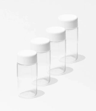 Four empty, clear plastic jars with white lids are arranged in a diagonal line on a white background.