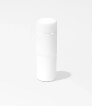A plain white cylindrical bottle with a rounded cap, standing upright on a white background, casting a faint shadow to the right.