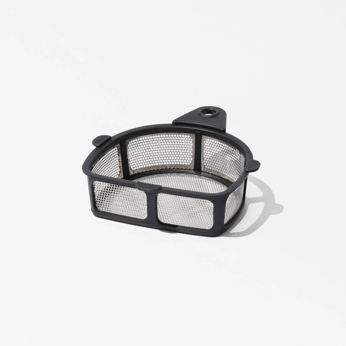 The Nama Pulp Strainer for J1 & C2 is a small, rectangular metal mesh filter basket with a black frame and a tab featuring a hole, casting a shadow on a white surface.