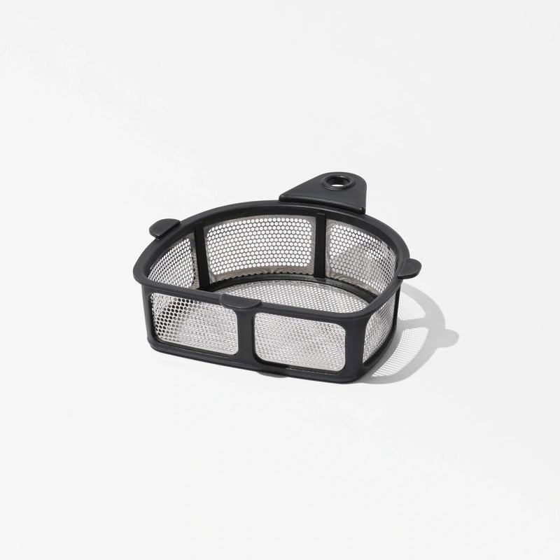 The Nama Pulp Strainer for J1 & C2 is a small, rectangular metal mesh filter basket with a black frame and a tab featuring a hole, casting a shadow on a white surface.