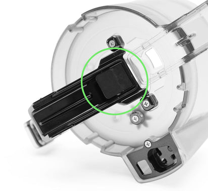 Close-up of a transparent plastic container from the Nama J2 Cold Press Juicer, with the Pulp Outlet Gasket—a black rectangular component—highlighted by a green circle and featuring visible screws and attachment points.