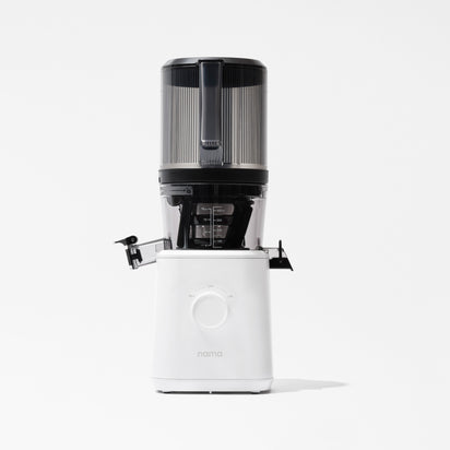 The Nama J2 is a modern cold press juicer in white and black, featuring a clear top container, side spout, and large front dial, shown against a plain white background.