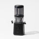 The Nama J2 Plug Type G is a sleek, modern black cold press juicer with a clear cylindrical top and a round front control dial. It features hands-free, easy-to-clean juicing and is shown on a plain white background with soft shadows.