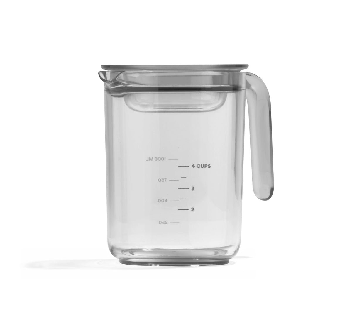 A transparent measuring cup from the Pitcher Set, featuring a handle and spout reminiscent of a milk pitcher, is filled with water up to the 4-cup mark. Clearly visible measurement lines and numbers are printed on the side, and the cup rests on a white background.