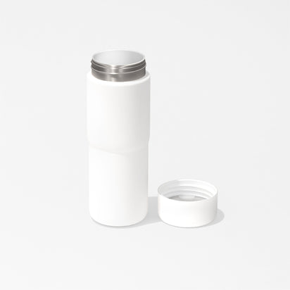 The Insulated On-the-Go Bottle, featuring a plain white design and stainless steel rim, stands upright on a white background with its matching cap placed open to the right.