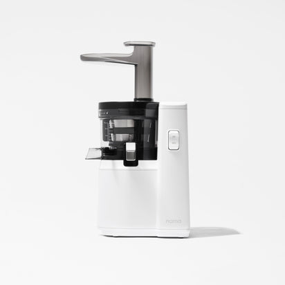 The Nama J1 is a modern cold press juicer in white and black, featuring a transparent juice container and chute, sleek minimalist design, front power button, and easy-to-clean components—shown here against a plain white background.