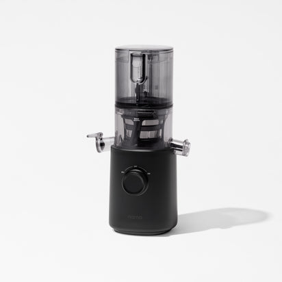 The Nama J3 is a sleek, modern black cold press juicer with a transparent top section and central dial. Shown on a plain white background, it features a spout, closed lid, is portable, and easy to clean.
