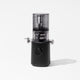 The Nama J3 is a sleek, modern black cold press juicer with a transparent top section and central dial. Shown on a plain white background, it features a spout, closed lid, is portable, and easy to clean.