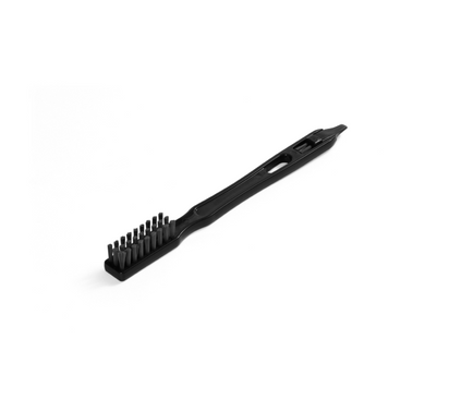 The Cleaning Brush for the Nama C2 Cold Press Juicer is black plastic with a rectangular head of short bristles, a handle with a central opening, and a notched end opposite the bristles, displayed on a white background.