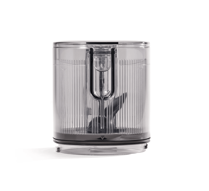 The Hopper Assembly is a transparent plastic container with a ribbed design and a central blade mechanism at the base, designed for chopping or blending, and is compatible with the Nama J3 Cold Press Juicer; shown against a plain white background.