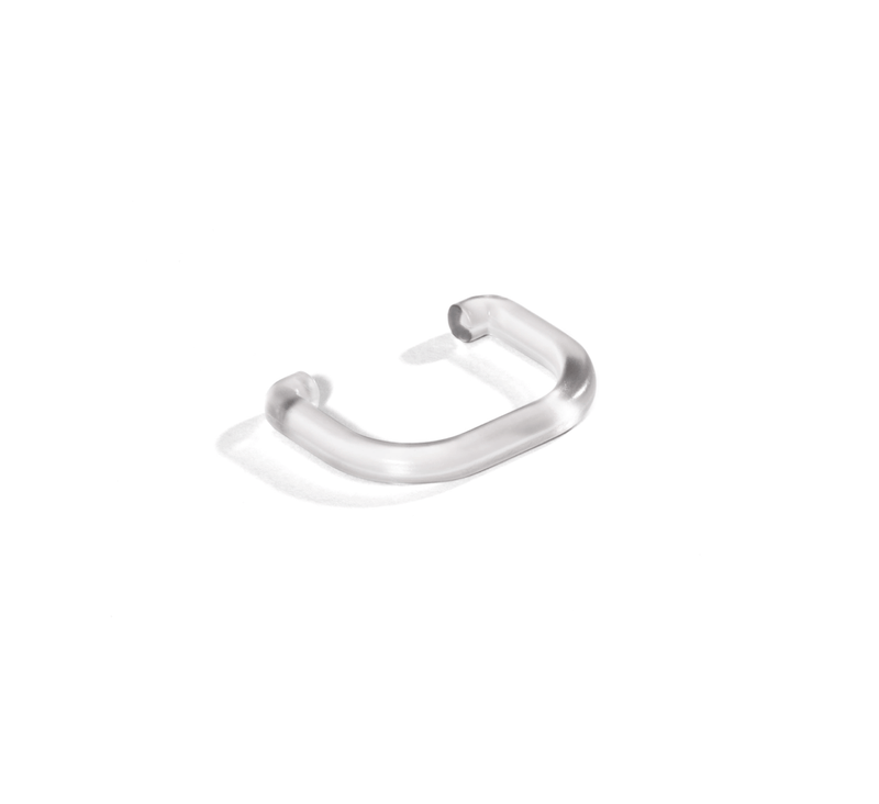 A small, transparent, U-shaped Pulp Outlet Loop—like the kind used with the Nama J3 Cold Press Juicer—is placed on a white background, casting a faint shadow.