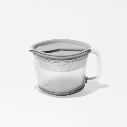The Large Pitcher Set includes a clear glass measuring cup with a handle, gray plastic lid, and custom-fit strainer for juice storage. Visible measurement markings are on the side. The set is displayed on a white background.